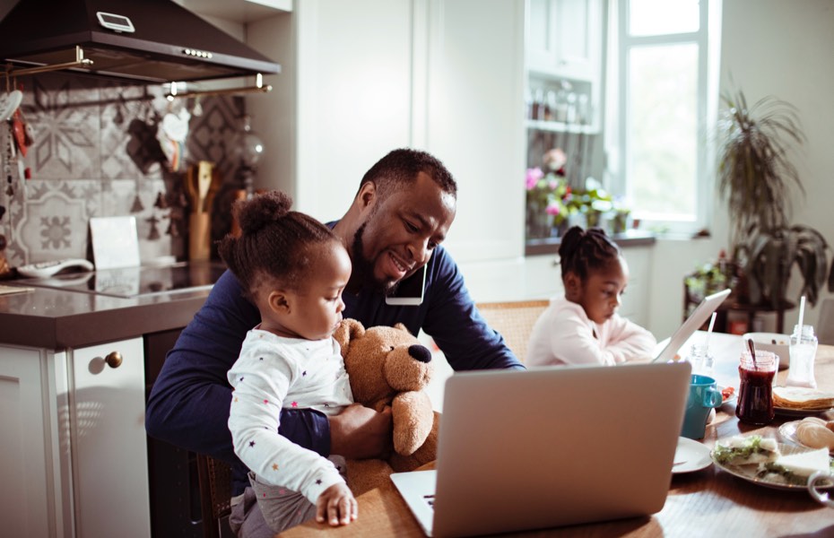 A father working at a computer next to his children.