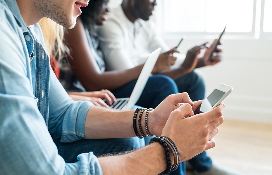 Several people working side by side with various mobile devices.