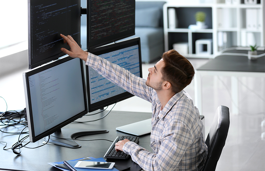 A man looking at code on a computer screen.