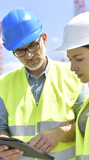 Two construction workers working at a tablet.