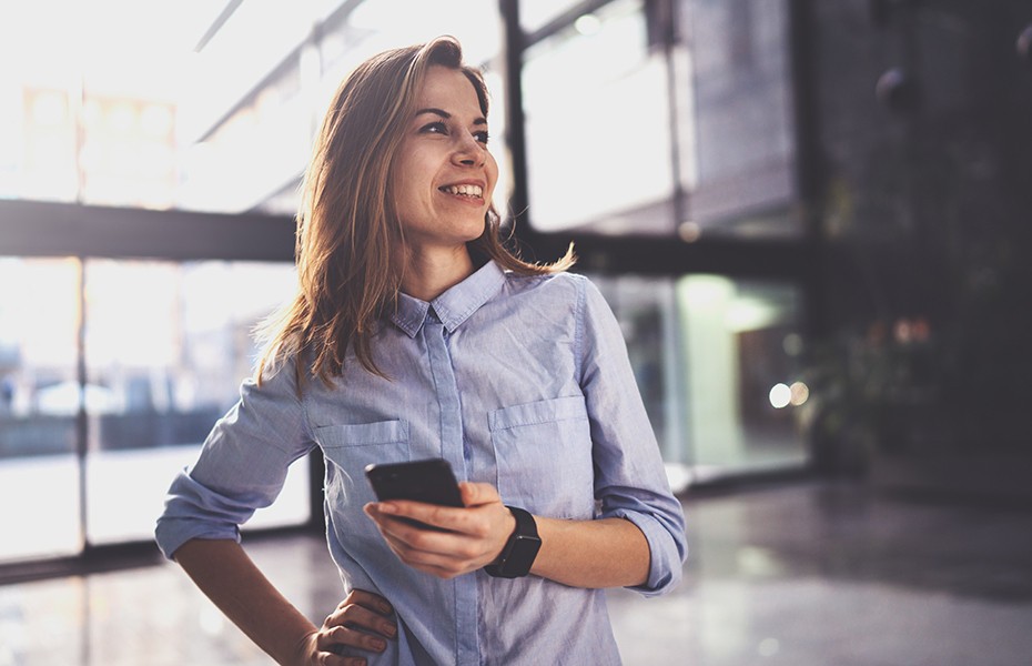 A woman holding a phone and looking into the distance.