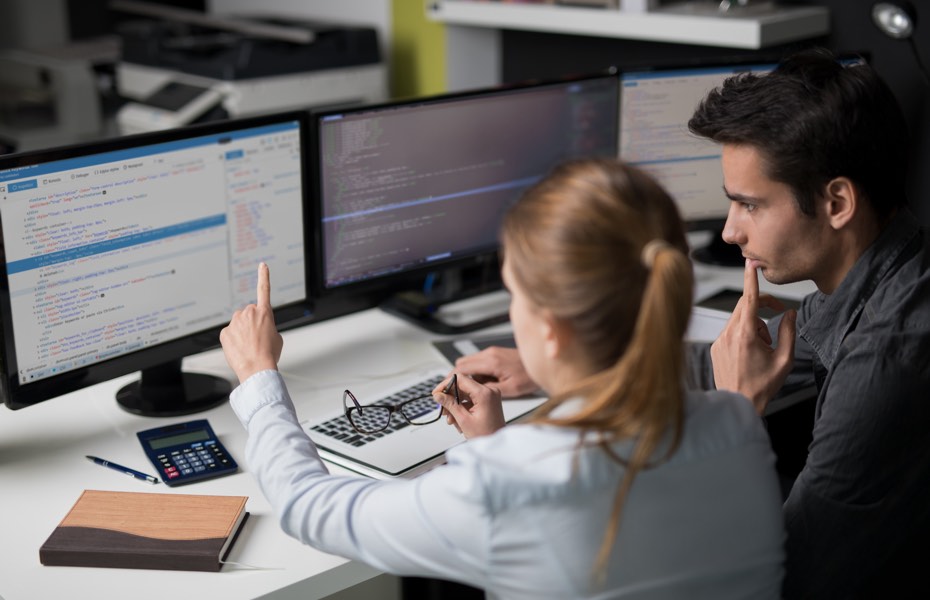 A young man and a young woman looking at code.