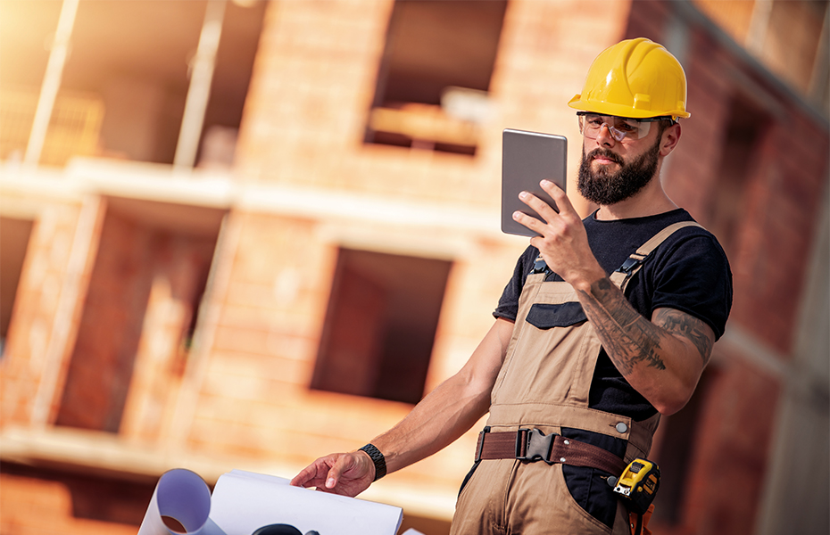 A construction worker looking at a tablet.