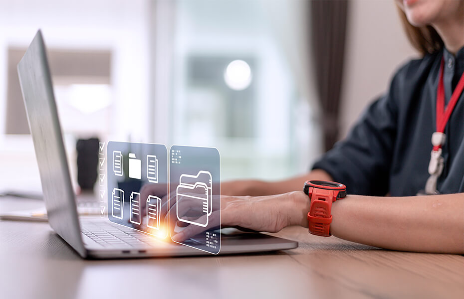 Professional in black business attire with a red identification badge working at a laptop with digital file management visualizations. Holographic overlays display folder and cabinet icons representing organized data systems and cloud storage.